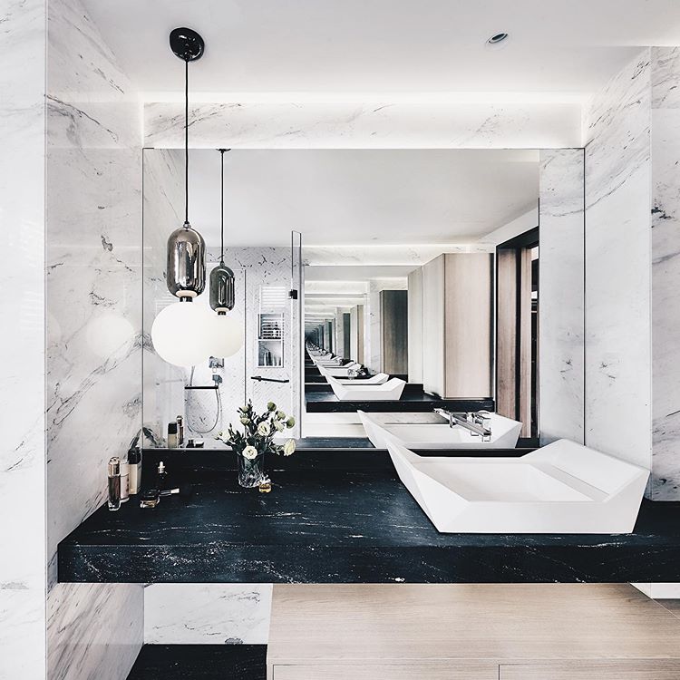 A bathroom with marble counter tops and a black sink.