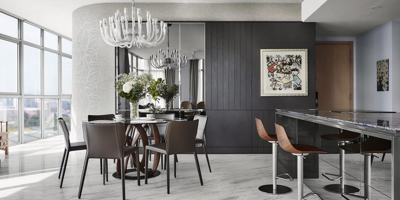 A modern kitchen with marble counter tops and a dining table.