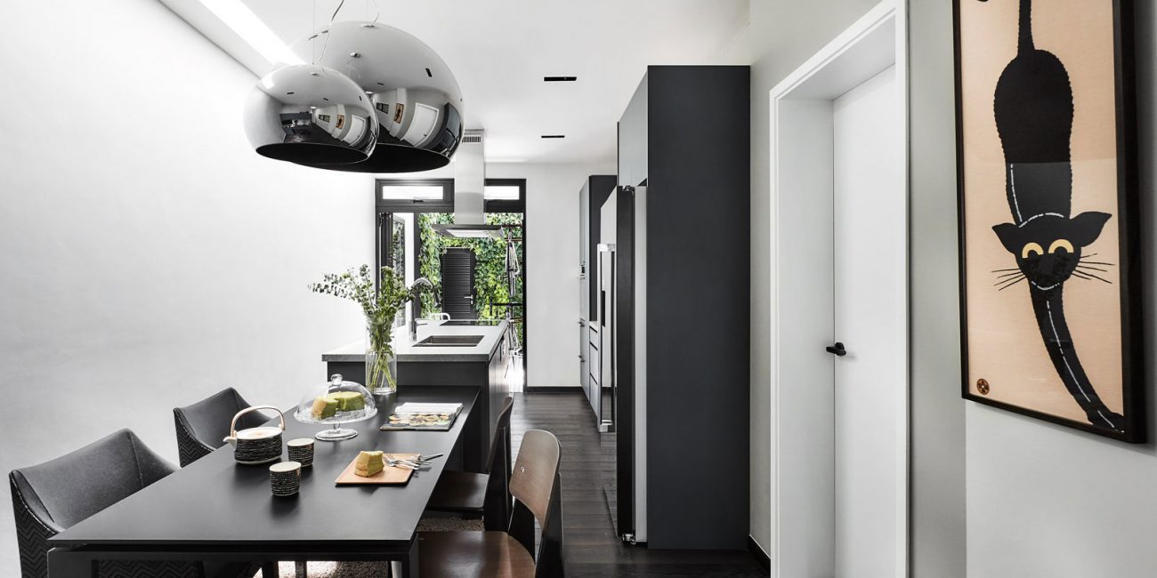 A black and white dining room with a cat hanging above the table.