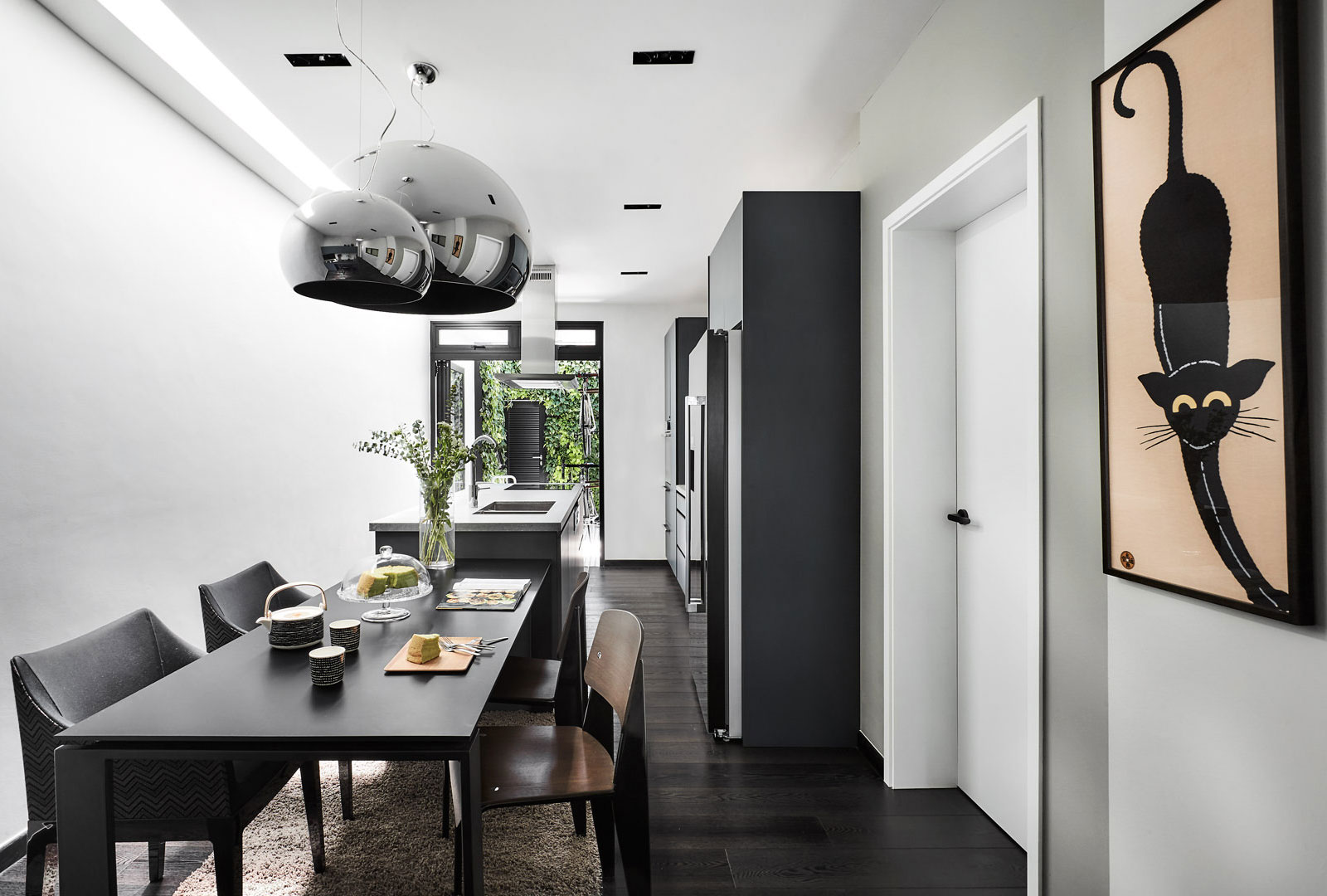 A black and white dining room with a cat hanging above the table.