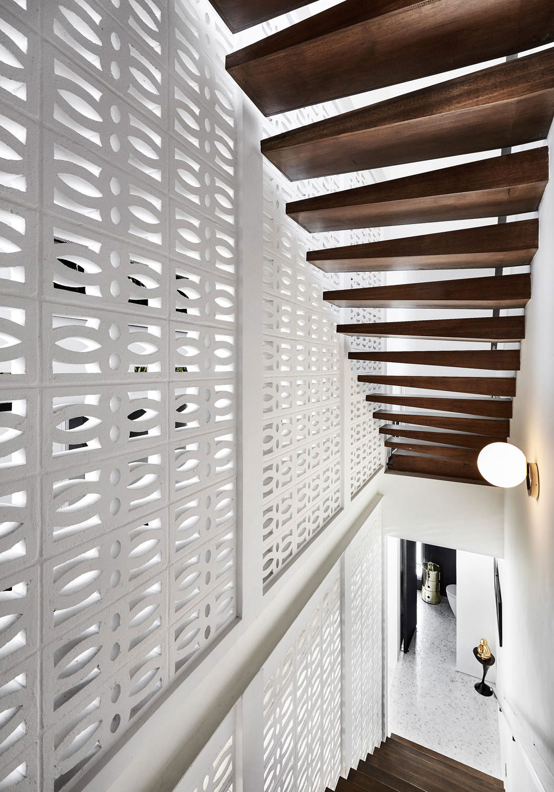 A white staircase with wooden slats and a white wall.