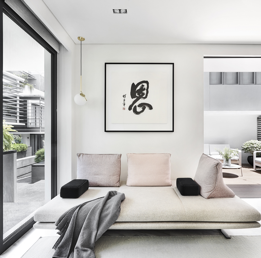 A living room with a white couch and chinese art on the wall.