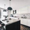 A white kitchen with black counter tops and stools.