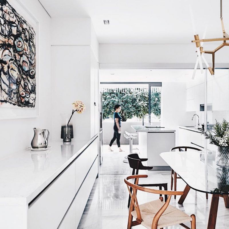 A white kitchen with a dining table and chairs.