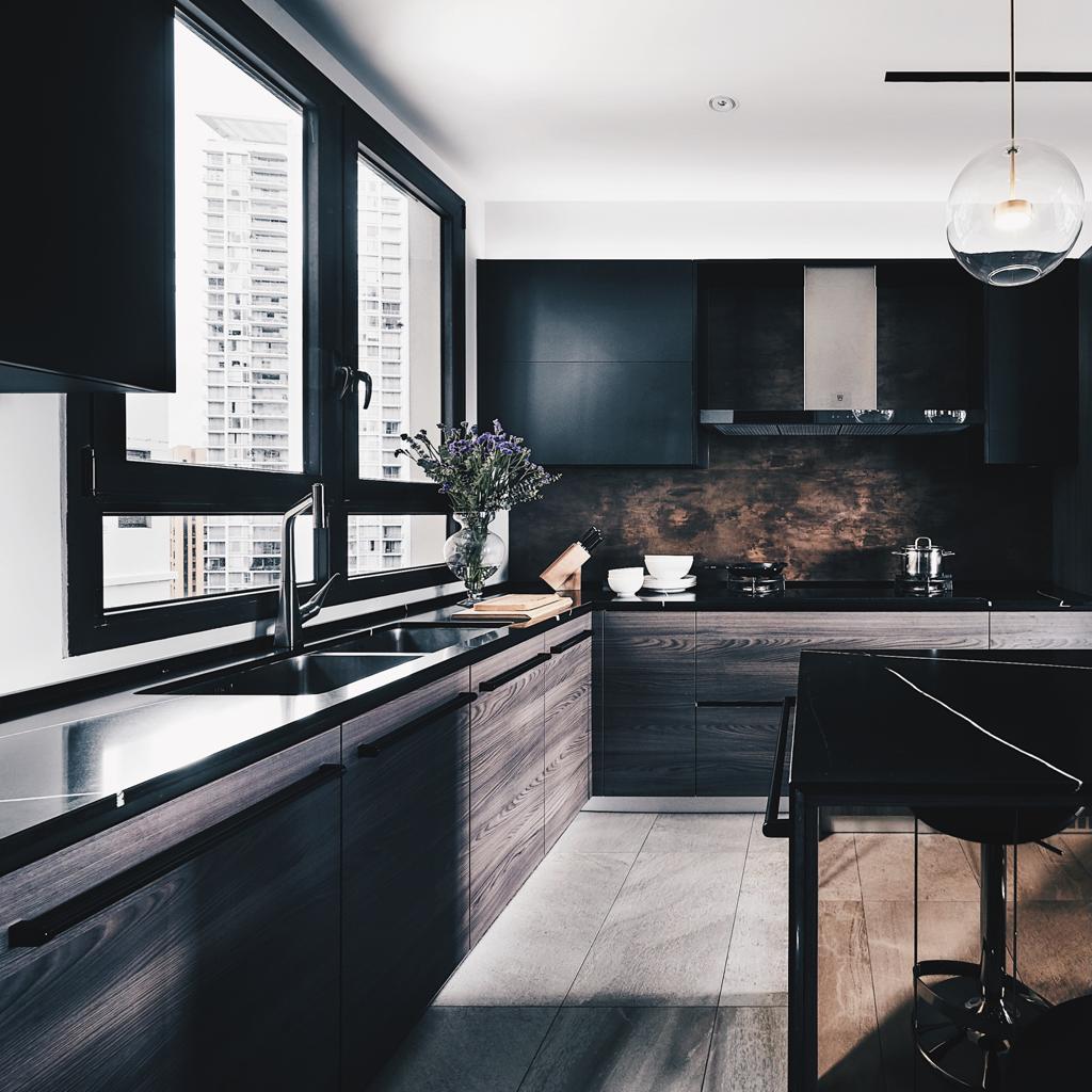 A modern kitchen with black cabinets and marble counter tops.