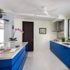 A blue kitchen with white cabinets and a ceiling fan.