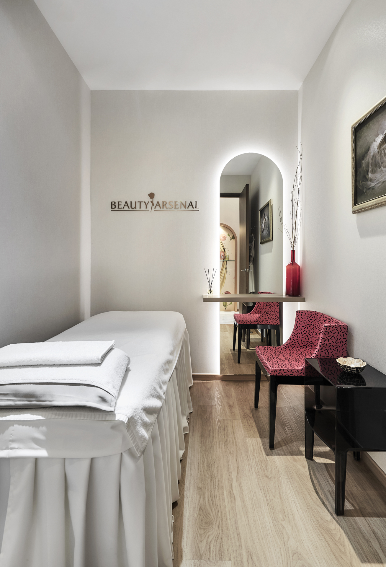 A beauty treatment room with a bed and a mirror.