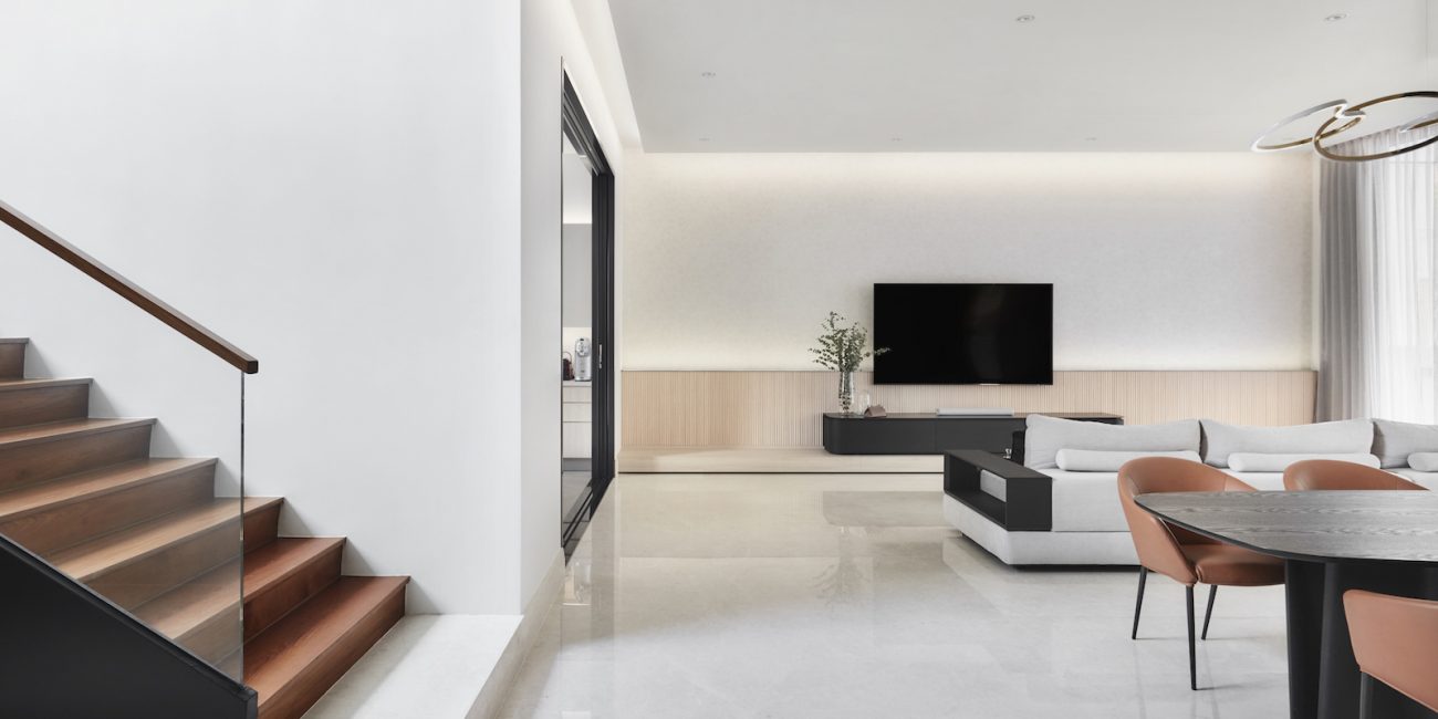 A modern living room with stairs and a television.