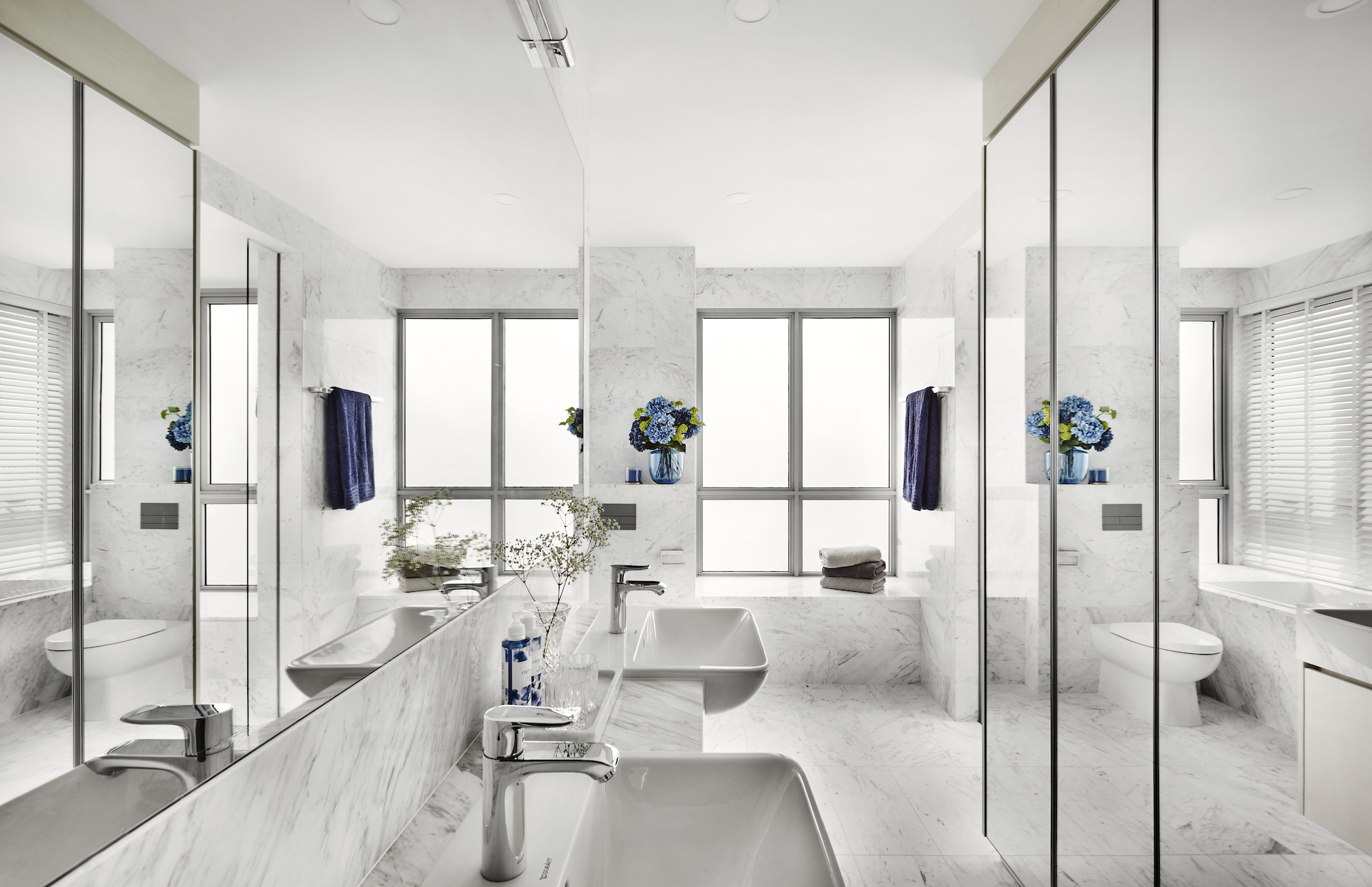 A white bathroom with marble floors and mirrors.
